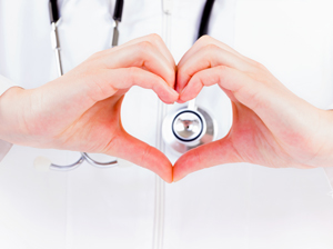 Picture of a close up of a Physician making a heart shaped with (his/her) hands in front of the stethoscope around (his/her) neck.