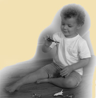 Picture of little Joel, (Joel Hutchins nephew) who looks somewhere between 4-5 playing with a toy and looking down smiling.
